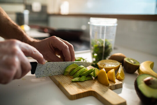 Person slicing avocado for smoothie in home kitchen