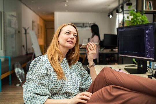 Young businesswoman using voice assistant at modern office desk