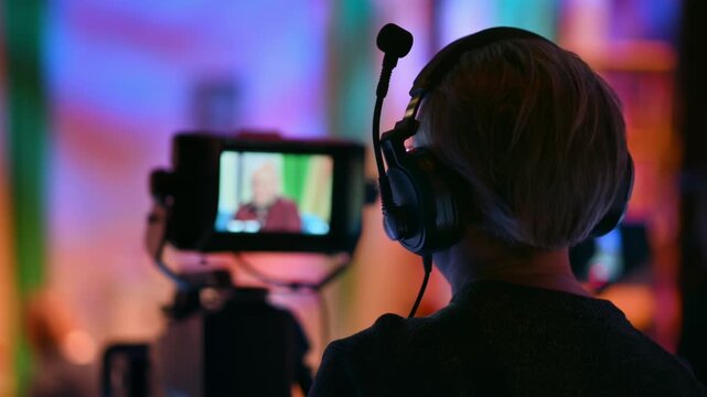 Camera operator using professional equipment to record a studio television program interview.