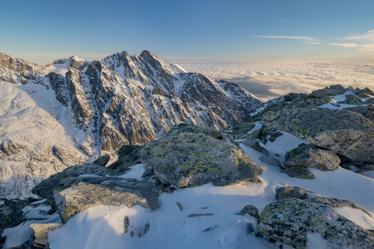 View of Slavkovsky stit peak with snow-covered slopes and rocky terrain under a clear blue sky above a sea of clouds Vysoke Tatry, Presovsky kraj, Slovakia.