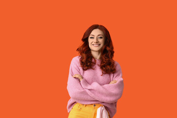 Obraz premium Beautiful young happy redhead woman on orange background