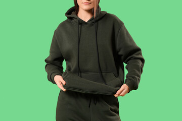 Obraz premium Young woman in sports suit on green background