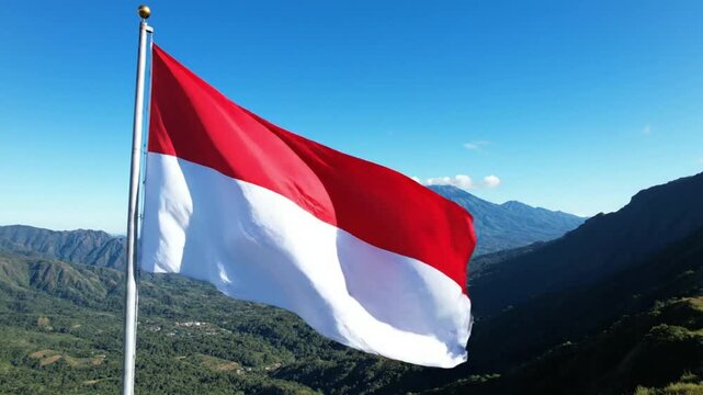 Indonesian flag waving on flagpole with mountain landscape background