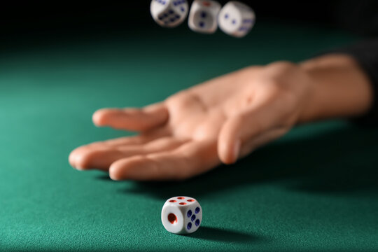 Male hand throwing white game dices on green background