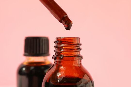 Bottle with iodine and pipette on pink background, closeup