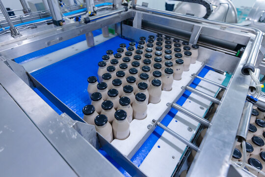 Automated beverage production line bottled drink moving along conveyor system hygienic food process facility modern packaging equipment ensuring quality control efficiency safe manufacturing standards