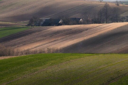 View of rolling agricultural hills and farm buildings in Ponidzie Park during early spring Busko-Zdroj, Swietokrzyskie, Poland.