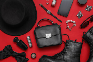 Obraz premium Composition with shoes, black hat, cosmetics and accessories on red background. Closeup