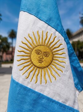 Argentina flag with golden sun symbol waving under a clear blue sky on a sunny day outdoors