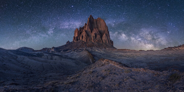 View of the iconic rock formation under a vibrant Milky Way and starry night sky in the desert Shiprock, New Mexico, United States.