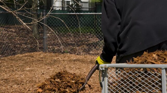 Close up look at a man scooping mulch out of a pull cart.