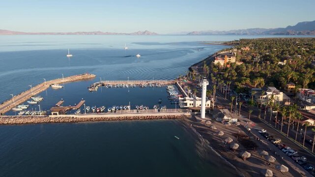 Watch the sun setting over Loreto Baja California Sur and its waterfront harbor filled with boats against desert mountains