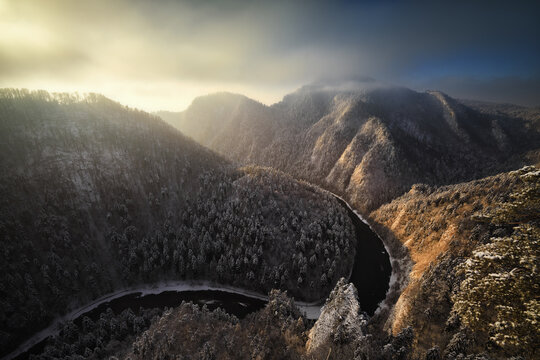 View of the Dunajec river gorge from Sokolica peak with snow-covered mountains and golden morning light in Nowy Targ County, Lesser Poland, Poland.