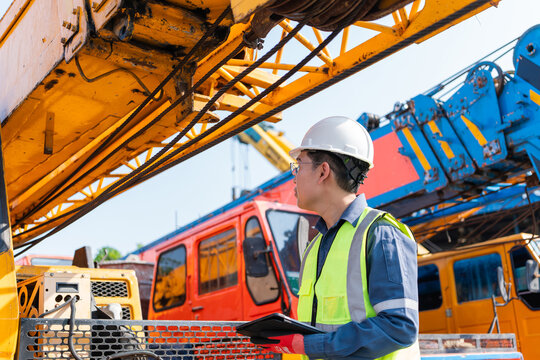Engineer inspecting crane machinery outdoor construction site