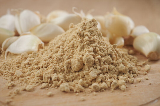 Ginger powder and garlic cloves on a wooden surface
