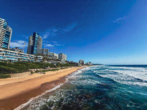 View of the sandy coastline of Umhlanga Rocks with modern high-rise hotels and apartments overlooking the Indian Ocean under a clear blue sky uMhlanga, KwaZulu-Natal, South Africa.