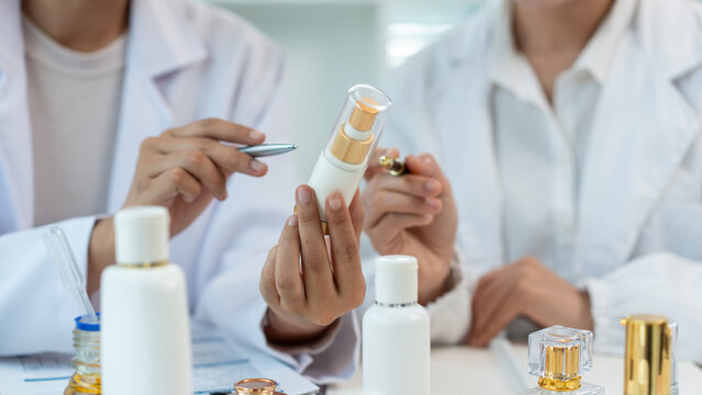Lab professionals examine a skincare bottle and cosmetic samples in a bright laboratory, showing product testing, research, and beauty development.