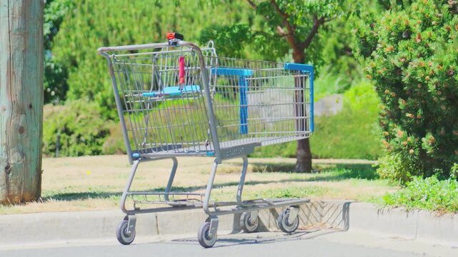 Empty metal shopping cart abandoned on asphalt cur