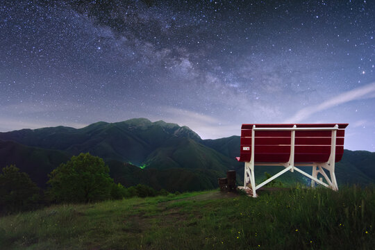 View of the Big Bench 404 overlooking the Apennine Mountains under a starry night sky with the Milky Way Pontremoli, Tuscany, Italy.