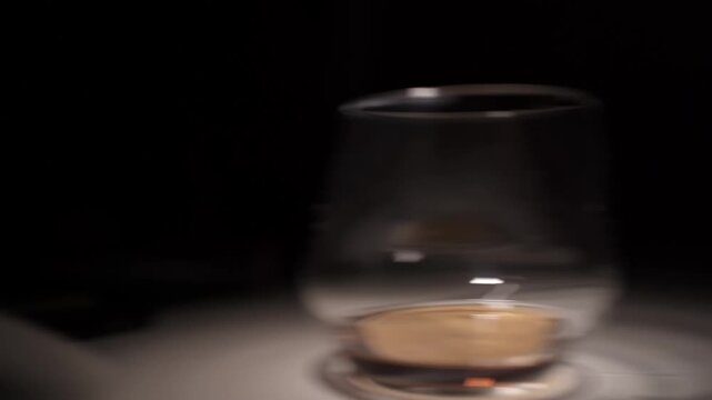 Hand Setting Down Glass of Cognac in Low Light Close Up