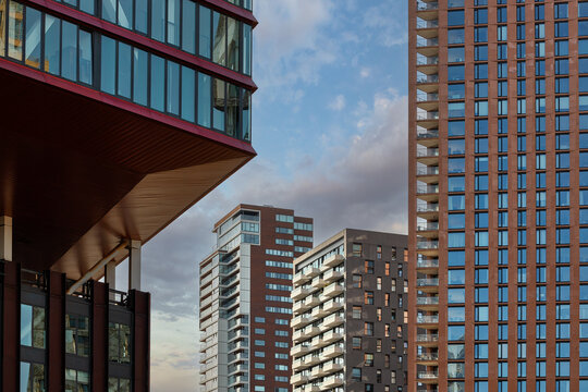 View of modern skyscrapers with glass facades and cantilevered architecture under a cloudy sky in Rotterdam, South Holland, Netherlands.