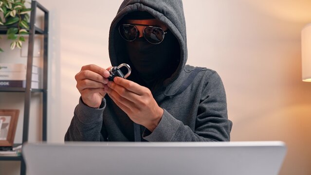 A hacker examines a combination lock, symbolizing the act of cracking security codes. The scene highlights cyber intrusion, password vulnerability, and the challenge of protecting digital information.