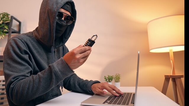 With a lock in hand, a masked hacker represents the ongoing battle between cyber attackers and security systems. The image reflects password breaches, encryption challenges, and digital safety risks.
