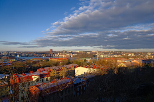 Gothenburg cityscape from Masthugget overlooking residential buildings with red roofs, the river, and a dramatic cloudy sky, Sweden