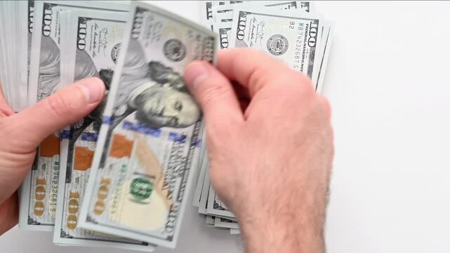 Hands counting stack of hundred dollar bills on white background.
