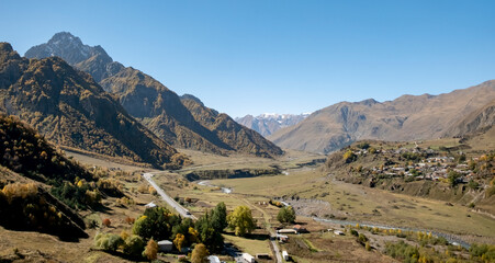 Fototapeta premium Scenic view of mountains and valley with small village during clear day in the Caucasus region of Georgia