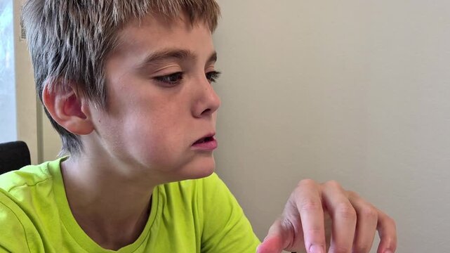 A teenage boy puts a piece of sandwich in his mouth and chews with gusto