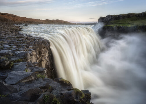 View of Dettifoss waterfall with powerful cascading water and rising mist over dark basalt rocks, Nordurthing, Iceland.