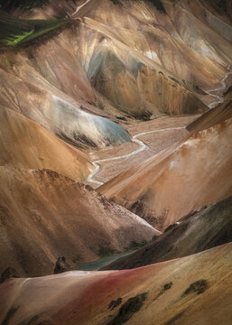 View of the colorful rhyolite mountains of Landmannalaugar with a winding glacial stream flowing through the volcanic valley in Rangarthing ytra, Iceland.