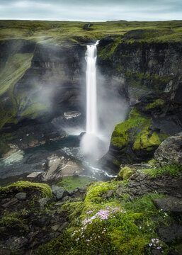 View of Haifoss waterfall cascading down steep mossy cliffs into a rocky canyon under a cloudy sky Skeida- og Gnupverjah, Iceland.