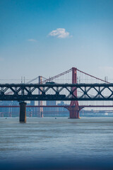 Fototapeta premium Telephoto view of multiple overlapping bridges spanning the Yangtze River in Wuhan, China, featuring a steel truss railway bridge and a red suspension bridge