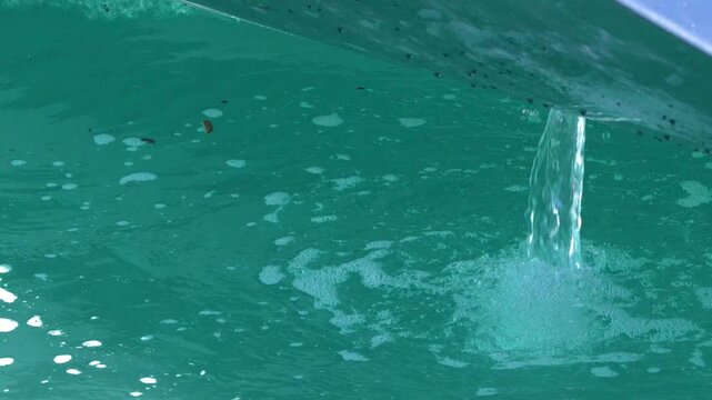 Bilge Pump Water Discharging from Boat Hull into Turquoise Sea