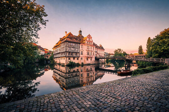 Bamberg old town hall reflecting in regnitz river at sunset