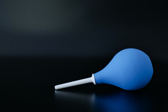 Blue rubber enema syringe bulb isolated on black background with clear view of medical hygiene device