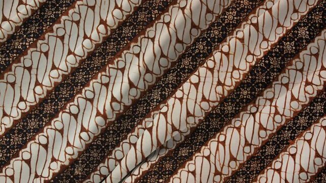 Abstract Batik Pattern: A close-up of a traditional Indonesian batik fabric showcases an intricate diagonal pattern of brown and white motifs, highlighting the art of wax-resist dyeing.