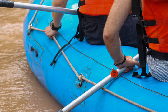 Thrilled people enjoy active outdoor sport adventure paddling blue raft in brown river water, holding paddle tightly with determined expression during extreme summer recreation