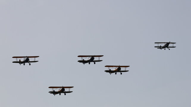 View of a formation of six vintage biplanes flying in a clear sky during an aviation event La Ferte-Alais, Ile-de-France, France.
