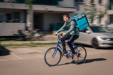 Fototapeta premium Young man delivering food by bicycle on city street