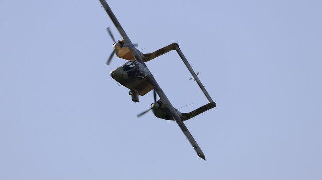 View of a vintage North American Rockwell OV-10 Bronco military aircraft performing a banking maneuver against a clear blue sky La Ferte-Alais, Ile-de-France, France.