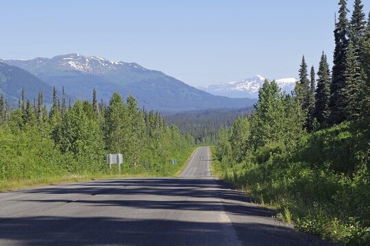 Road leads as an endless grade through forest and snow-capped mountains, wilderness, Stewart Cassiar Highway, British Columbia, Canada