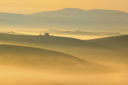 Morning atmosphere in Tuscany, hilly landscape with fog glowing in first light at sunrise, Val d'Orcia, Tuscany, Italy
