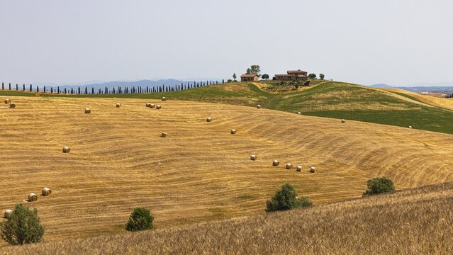 Straw bales on harvested field, behind a country house on a hill, near Ville di Corsano, Tuscany, Italy