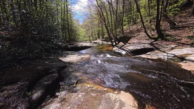 Rocky river with smooth water flow over flat stone surface