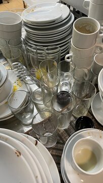 Dirty restaurant dishes photo with stacked plates, used glasses, coffee cups and food residue in busy kitchen washing area, hospitality cleanup, catering service and hygiene concept