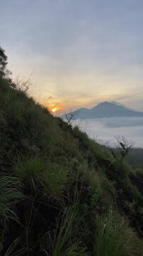 Trunyan and Abang Hills seen afar from Mount Batur in Kintamani, Bali, during golden sunrise with blue sky and scattered clouds in the morning. Concept of mountain hiking, adventure, and tourism