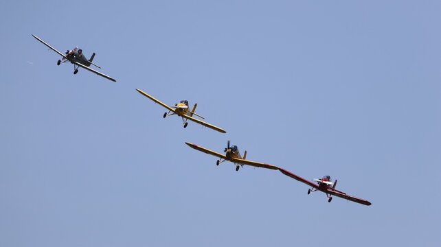 View of four vintage propeller monoplanes flying in formation during an airshow against a clear blue sky in La Ferte-Alais, Ile-de-France, France.